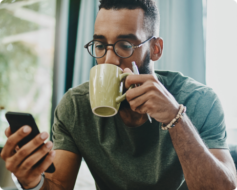 Man Drinking Coffee and looking at his phone.