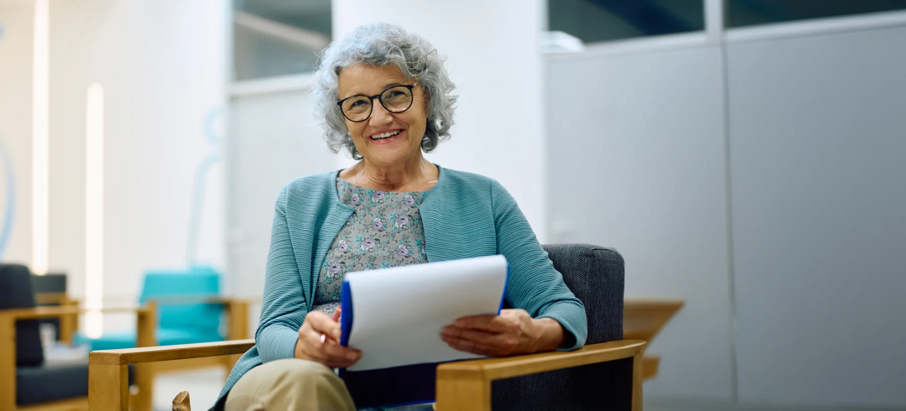 older woman smiling looking at clipboard in waiting room
