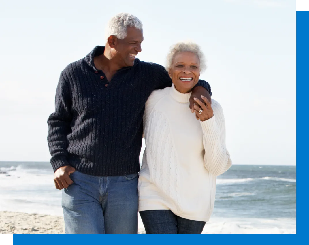 elderly couple embracing each other smiling on the beach
