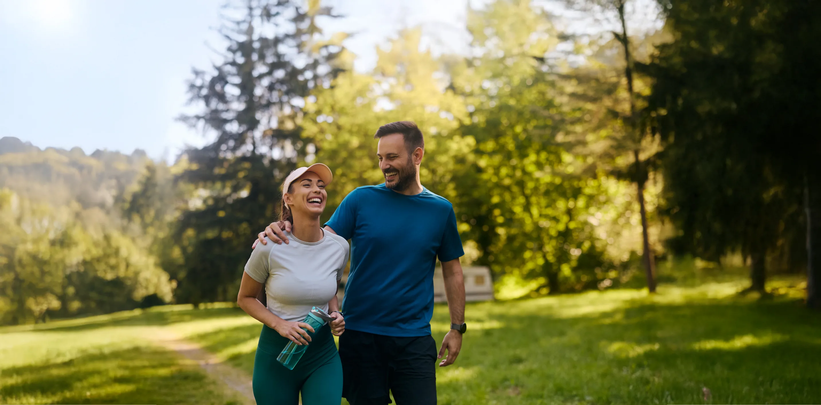 Couple outside on a tennis court smiling while holding their tennis racquet