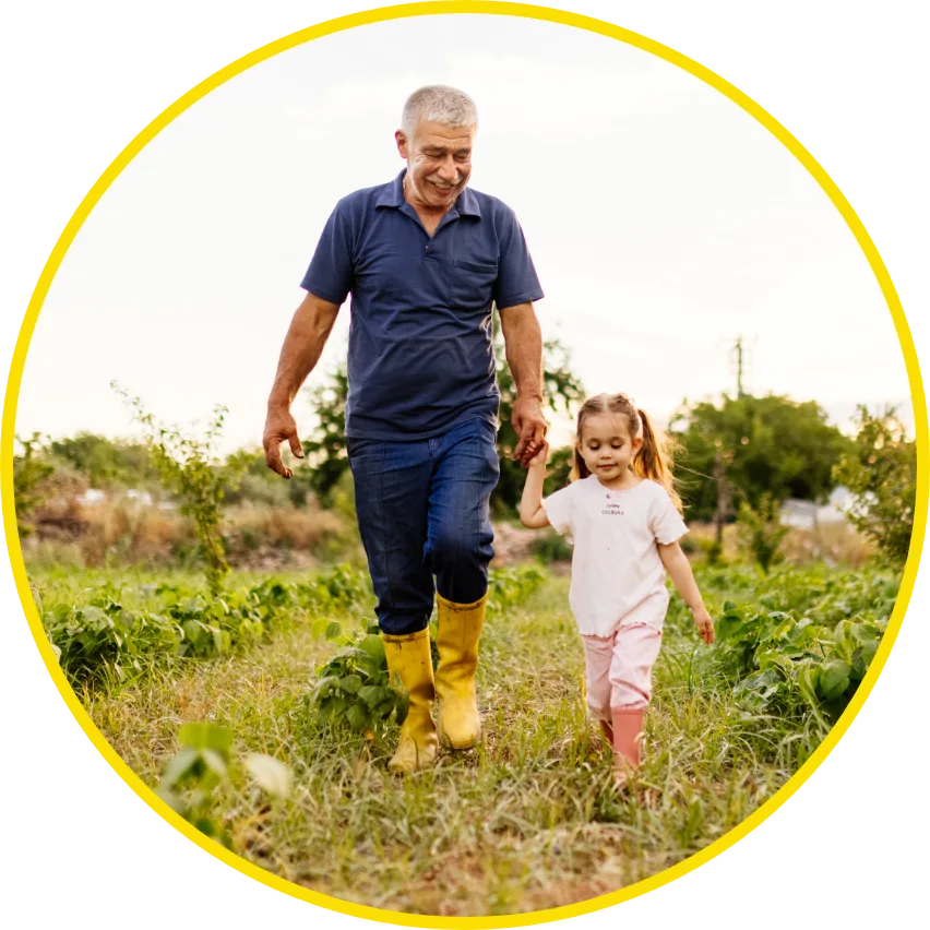 Older gentleman walking with a little girl in a vegetable patch